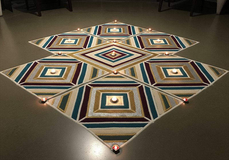 A rangoli design featuring interlocking geometric shapes like squares and triangles